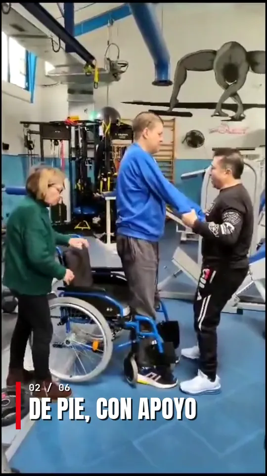 Usuario poniéndose de pie con ayuda durante una sesión de rehabilitación